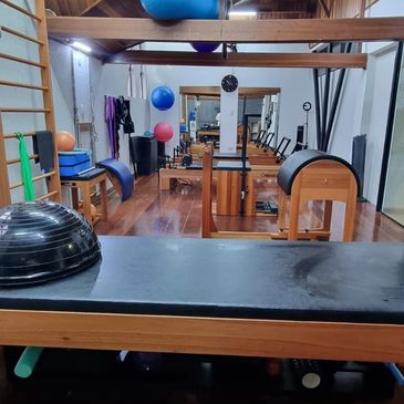 A clean Pilates studio with various exercise equipment and wooden flooring.