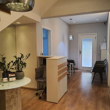 Modern reception area with chairs, a desk, and plants in a well-lit room.