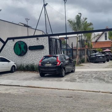 Modern building with a green logo and parked cars under a cloudy sky.