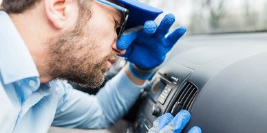 Man inspecting car dashboard closely.
