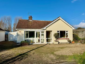 A single-story house with a tiled roof and front garden under a clear blue sky.