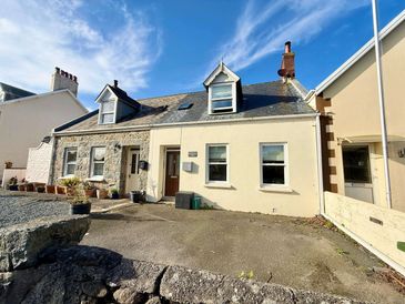 Cozy two-story stone and plaster house under a blue sky.