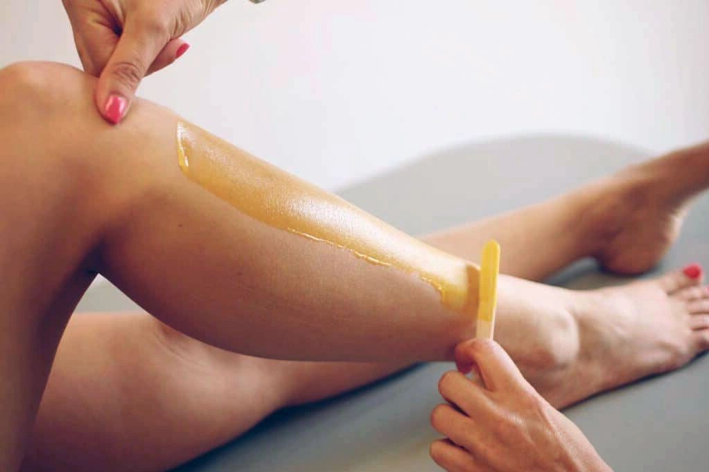 Person applying wax for leg hair removal.