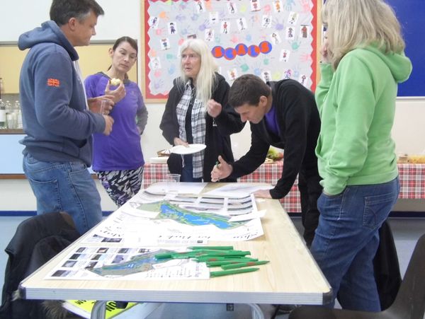 five people in workshop talking around table with pencils and paper 