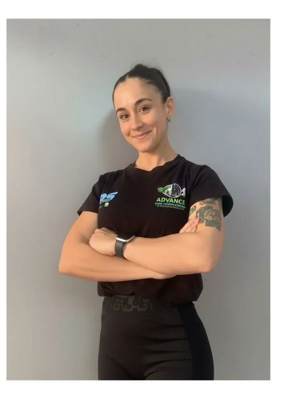 Confident woman with crossed arms, wearing a black t-shirt and leggings, smiling softly.