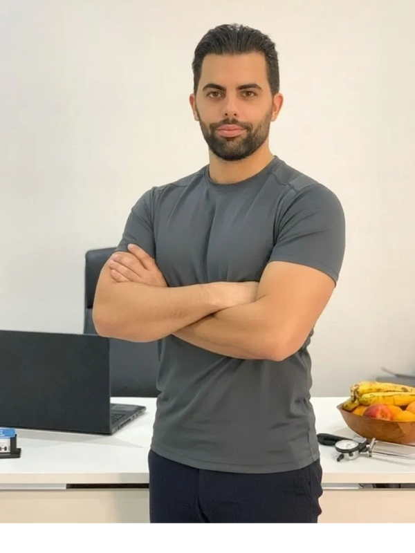 Man standing confidently with arms crossed in a modern office setting.