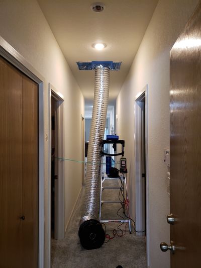 Temporary ventilation setup in a hallway with ducting and a fan.