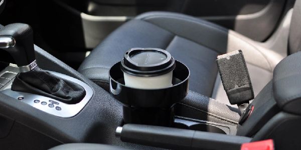 A large cup of coffee in a car cup holder adapter. Cup Holder Adapter for car securely holding a cup of coffee.