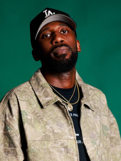 Man wearing a beige jacket and black LA cap.