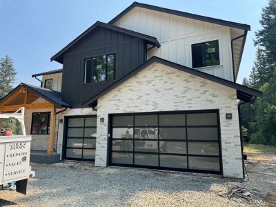 New construction home with black framed glass garage doors by Door Doctor Services