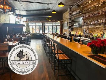 Cozy bar interior with wooden stools and warm lighting.