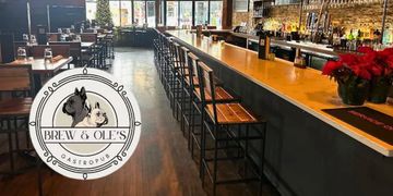 Cozy bar interior with wooden stools and warm lighting.