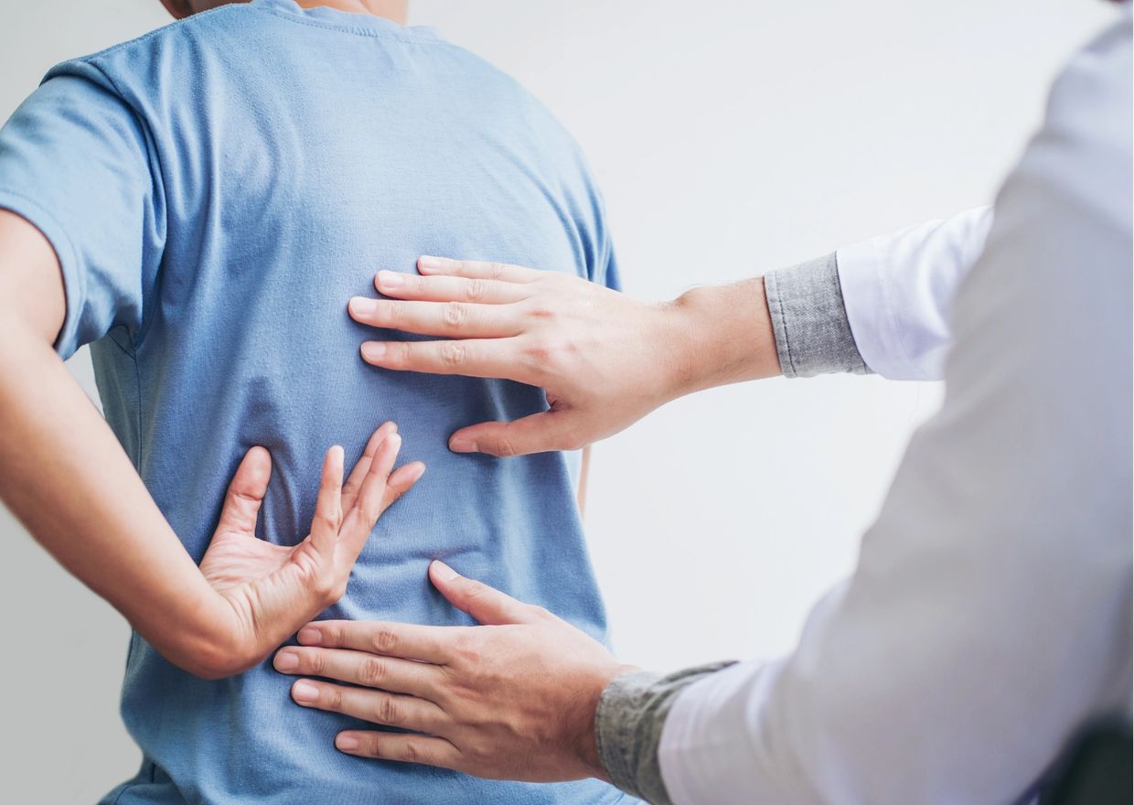 A person with back pain being helped by a physiotherapist.