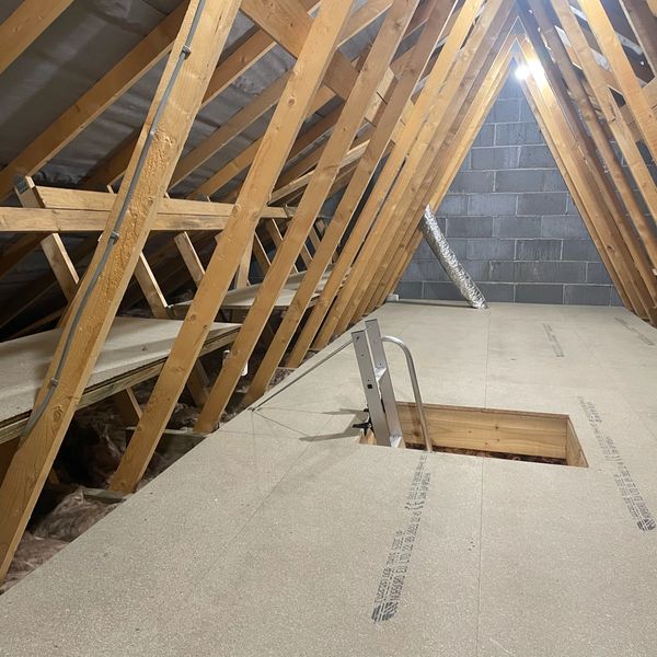 A clean, newly floored attic with wooden beams and insulation.
