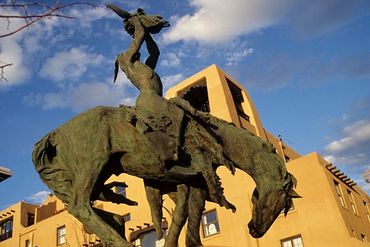 Santa Fe, New Mexico, Native American sculpture with adobe style building behind.