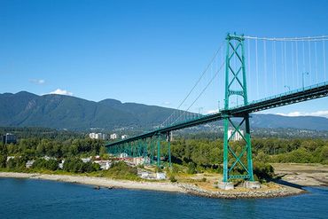 Vancouver, British Columbia, Canada, Suspension bridge spanning inlet with mountains in background.