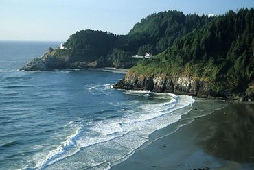 Florence, Oregon, Haceta Head Lighthouse perched atop cliff, waves from Pacific Ocean rolling in.