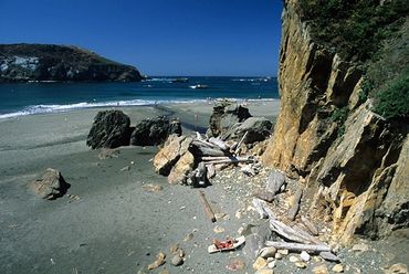 Harris Beach State Park, Oregon, Woman sunbathing on beach next to cliffs, on Pacific Ocean.