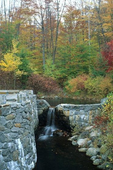 Franconia Notch State Park, New Hampshire, Waterfall flowing over stone wall with autumn colors.