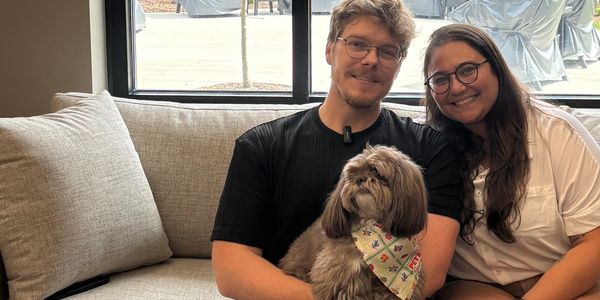 Couple sitting on a couch with a dog.