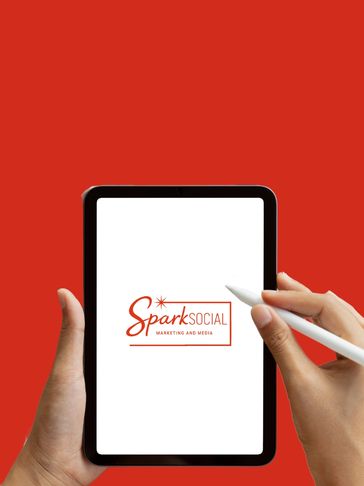 Person holding a tablet displaying the Spark Social Marketing and Media logo with a stylus.