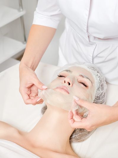 A woman receiving a facial mask treatment at a spa.
