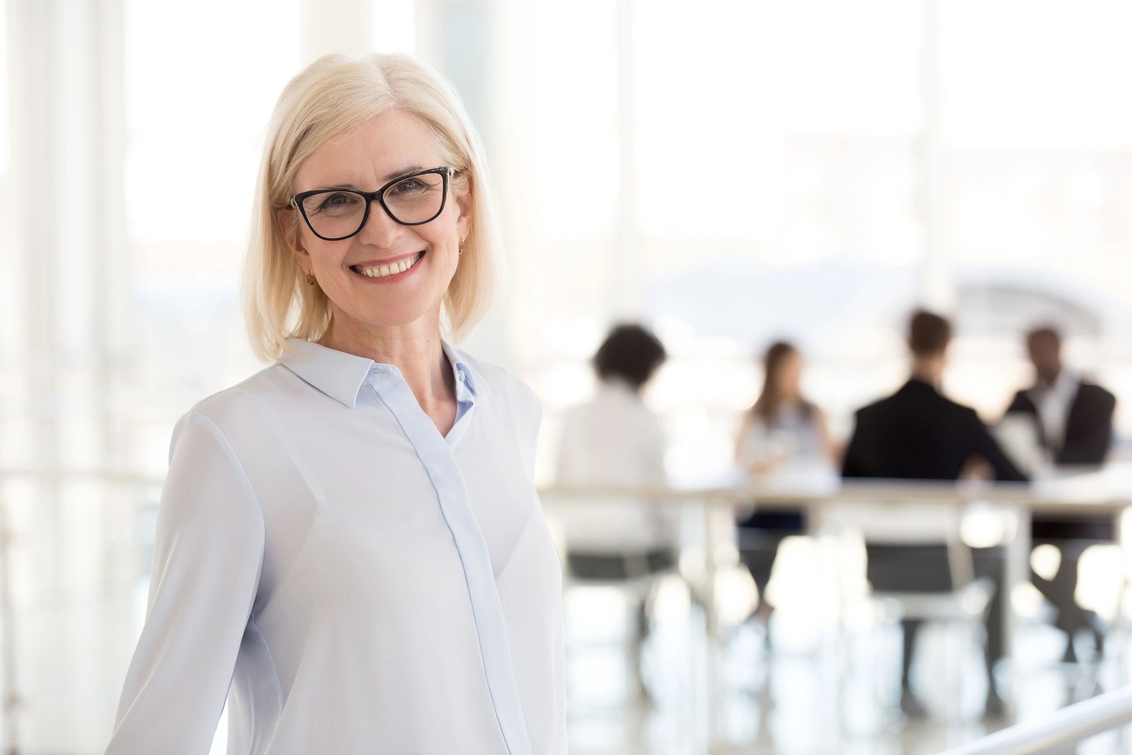 Tailored HR solutions: Woman smiling with team collaborating in office.