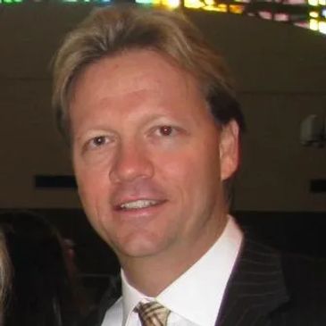 Man in suit and tie smiling for a photo.