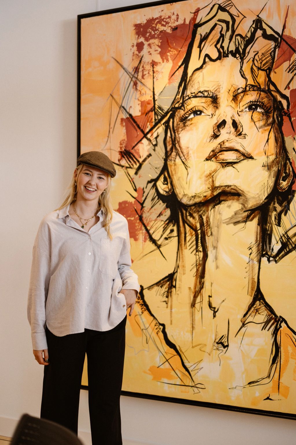 Vrouw poseert voor opvallend kunstwerk in warme tinten.