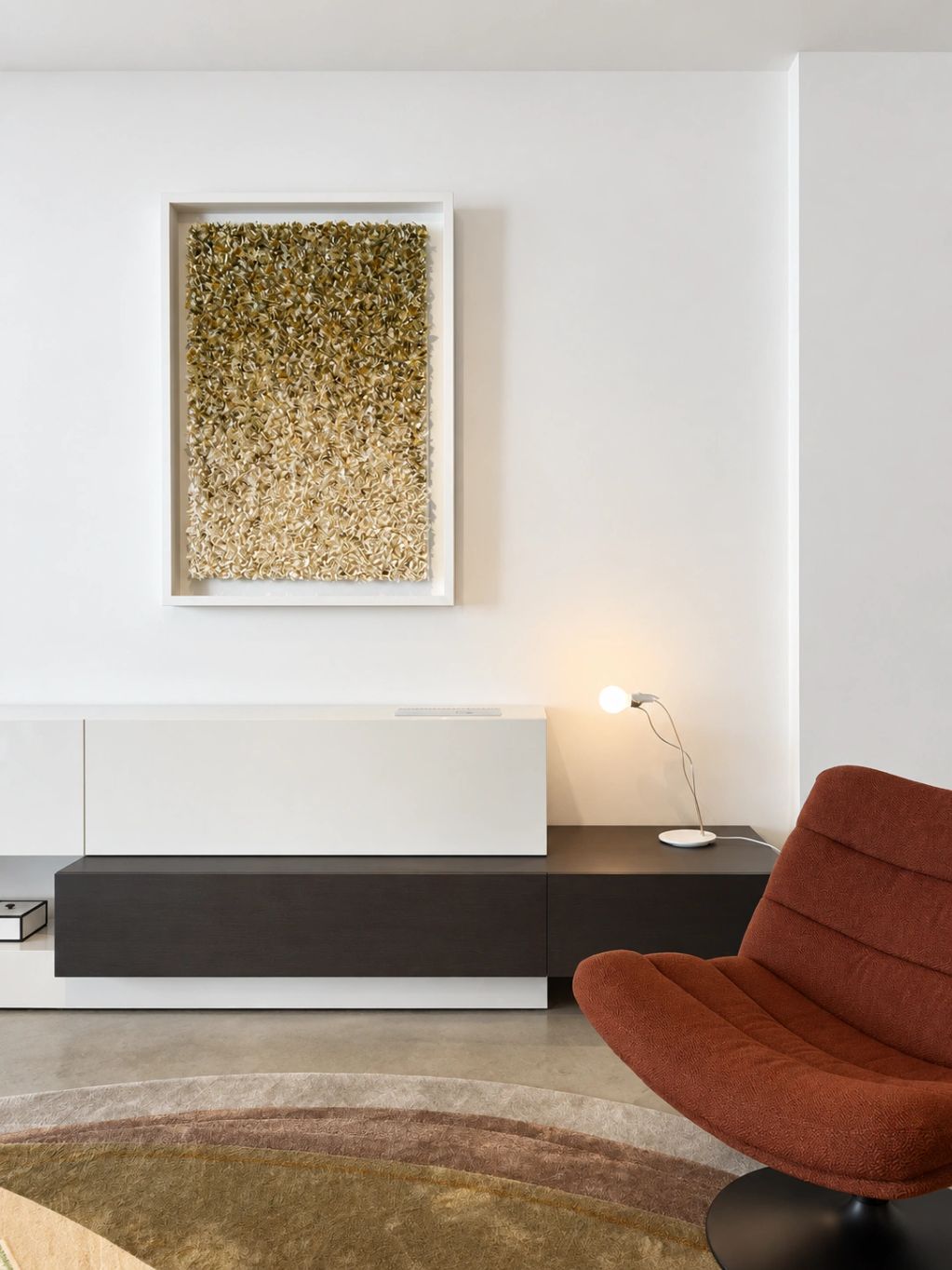 Moderne woonkamer met kunstwerk, lamp en comfortabele stoel.