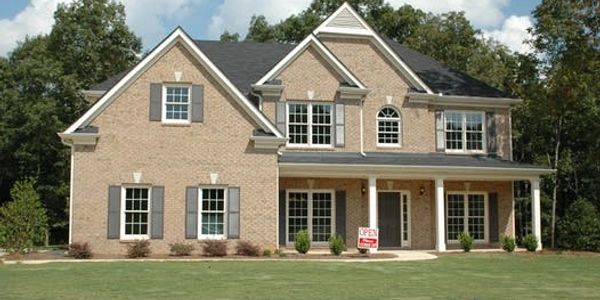 Two-story brick traditional home with gray shutters.