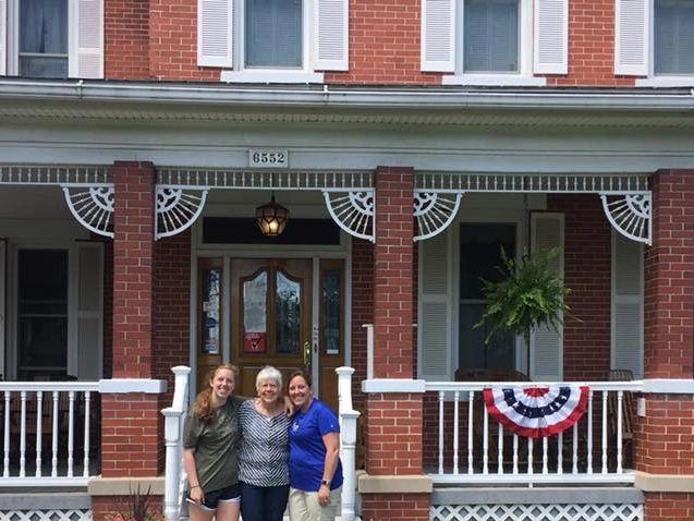 Three people standing in front of the campground's brick house.