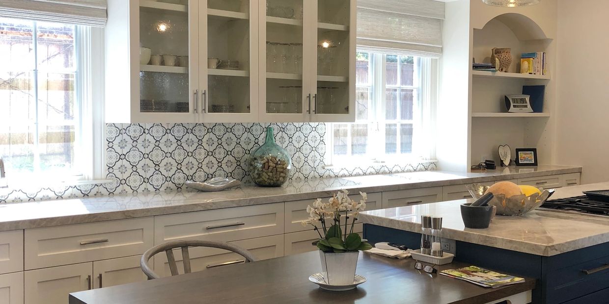 Bright modern kitchen with white cabinets and patterned backsplash.