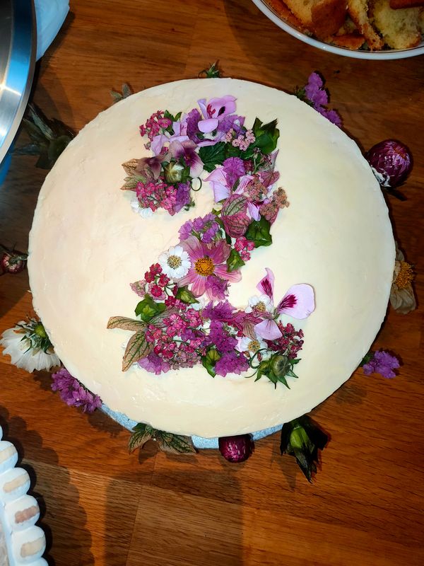 Top of a white cake with the number two made out of fresh flowers