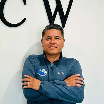 Man standing confidently with arms crossed, wearing a blue jacket.
