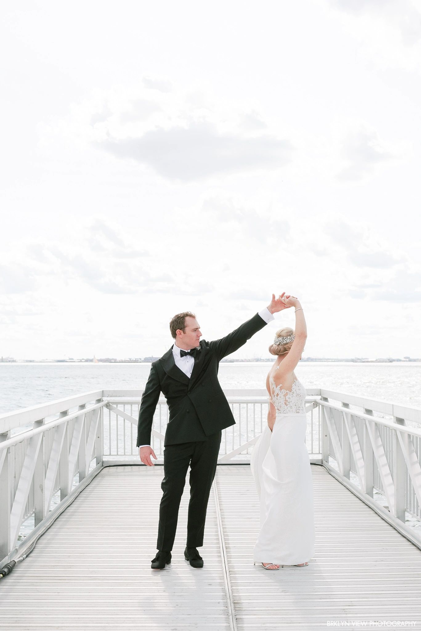 Groom dancing with bride on a pier