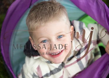 Smiling young boy with blue eyes inside a colorful tunnel.