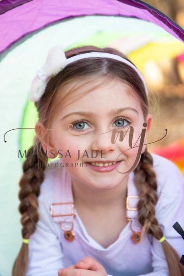 Smiling young girl with braided hair and a white headband.