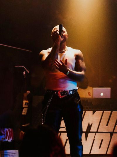 Musician performing with microphone under stage lights.