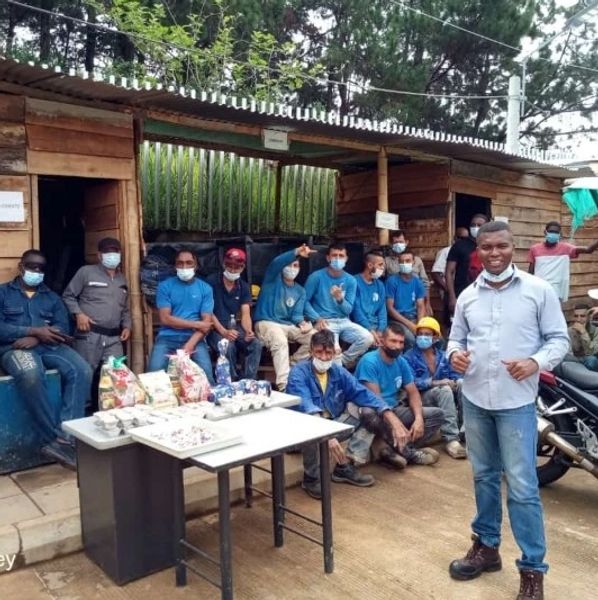 Grupo de trabajadores posando fuera de un taller con mesa y suministros.