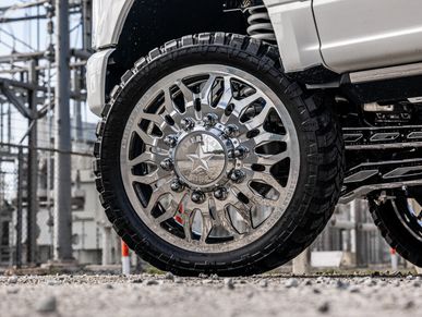 Close-up of a lifted white Ford F-350 with large chrome wheels.