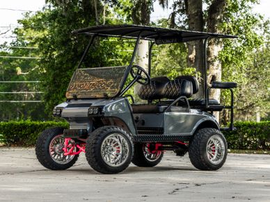 Custom lifted golf cart with large tires and black leather seats.