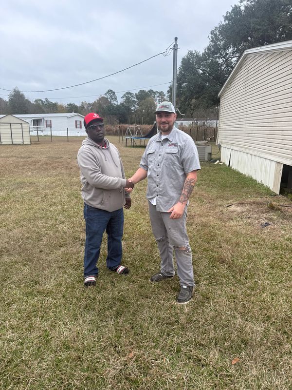 The owner of Serranos's plumbing services shaking a local residence hand after clearing a drain.