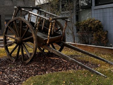 Old wooden cart displayed outdoors near buildings.