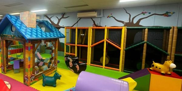 Colorful indoor kids' play area with soft structures and a playhouse.