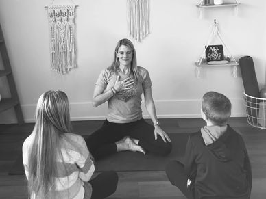 Woman leading a meditation session with two children.