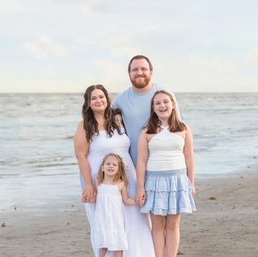 Family of four posing happily on a beach.