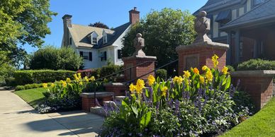 Elegant garden entrance with yellow flowers and bust statues.