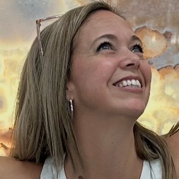 A woman smiling and looking upwards with a joyful expression.
