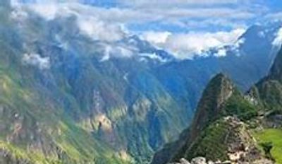 Ancient Machu Picchu ruins nestled in the Andes mountains under a blue sky.